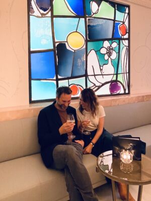 The Wick - Annie Morris and husband Idris Khan in The Painter's Room bar at Claridge's with her stained glass window (Courtesy of Annie Morris)