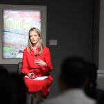 Christie’s Katharine Arnold captivates the audience while speaking, dressed elegantly in a striking red dress.