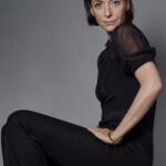 A woman, Mary McCartney, sits posing for a picture wearing an all black outfit.