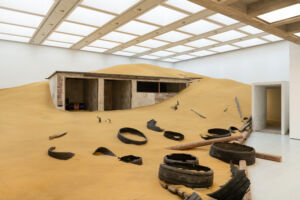 The Wick - Installation view of Mike Nelson, Triple Bluff Canyon (the woodshed), 2004. Various materials. M25, 2023. Found tyres. Photo: Matt Greenwood. Courtesy the artist and the Hayward Gallery.
