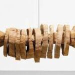 A wooden sculpture of a skeleton by Georg Baselitz hangs from the ceiling.