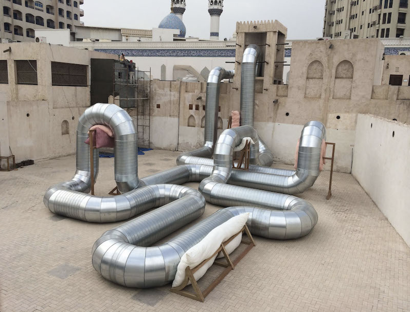 The Wick - Holly Hendry, ‘Homeostasis’, 2014. Galvanised steel ducting, meranti wood, cushions, fan, air.
Installed at Courtyard C, Sharjah Art Foundation, Sharjah, United Arab Emirates (2014). Copyright Holly Hendry. Courtesy the artist and Stephen Friedman Gallery, London and New York. 