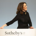 A woman with dark hair, Sotheby's Europe Chairman Helena Newman, stands for an auction wearing all black and smiling.
