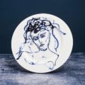 A white plate featuring a drawing of a woman's face, created by artist Tracey Emin.