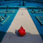 Photograph by Erik Madigan Heck of blonde woman in red gown running towards a manicured English garden