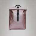 A pink rolltop backpack by the brand Rains featuring black fastenings.