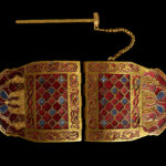 An ornate gold clasp with shades of red and blue.