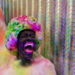 A sculpture by Lauren Halsey depicting a woman's head screaming set in a colourful shape against a backdrop of CDs.