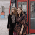 Two women, Katy Wickremesinghe and Touria El Glaoui, smiling in front of a red bus by Slawn
