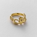 A gold ring by Alex Monroe and Emma Dabiri on a white background featuring two hands holding a heart.