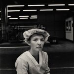 A black and white photo by Sibylle Bergemann depicting a woman working in a factory wearing a hair net.