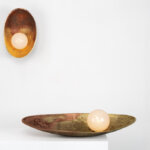 Two artistic metal dishes with light bulbs photographed against a white backdrop