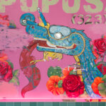 Large blue cartoon dragon with its tongue out on a pink background with red, orange, and pink flowers.