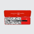 Black and white pen with white doodles by Keith Haring in a red box.