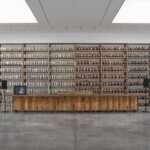 Wooden shelf with lots of ceramic vases in a large white and grey room