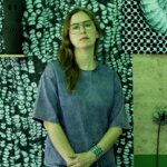 Woman with glasses standing in front of artworks
