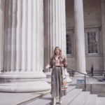 Woman wearing a skirt and pink top walking down large stairs.