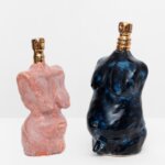 Two perfume bottles. One is pink and the other is blue of naked female and male figures