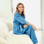 Woman wearing a blue boiler suit sitting on a white sofa