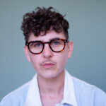 A person wearing glasses a white and blue shirt