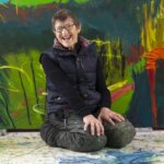 A woman sat on her knees in front of a green artwork