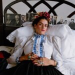 A woman dressed like Frida Kahlo lying on a bed