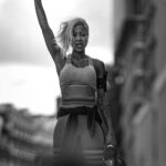 A black and white photograph of a woman holding her hand up
