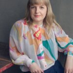 A blonde woman wearing a patterned shirt