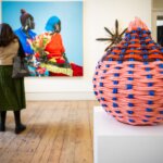 A sculpture and paintings in a gallery