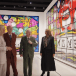 A photograph of two women and men walking in a gallery
