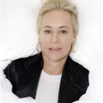 A woman with blonde hair lying in white sheets