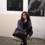 A woman sat on a chair in a painters studio