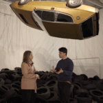 Two people standing under a car