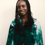 A photograph of a Black woman wearing a green top