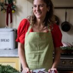 A woman wearing a green apron and red top in a kitchen